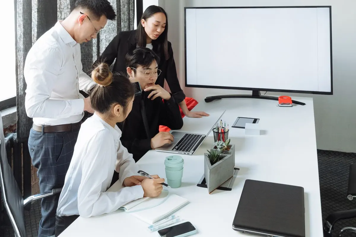 パソコンの前で使い方を相談する社員たちのイメージ