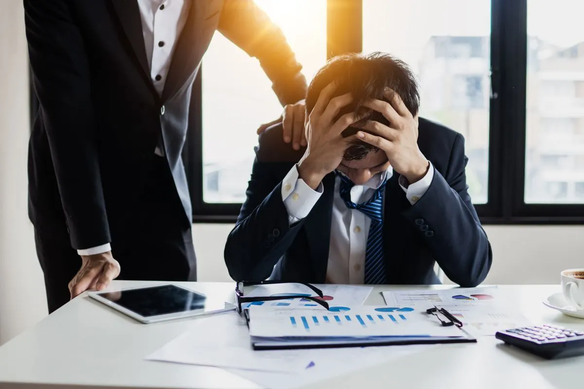 資料を前に頭を抱える経営者のイメージ